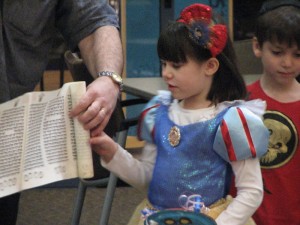 Photo by Ms. R. Gina Renee. Kindergartener Emily Ball holds the Megillah out for everyone to see.