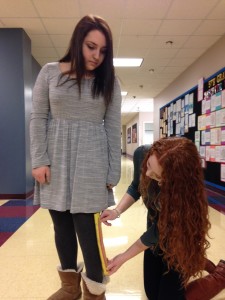Sophomore Leah Sosland  measures the length of freshman Amanda Sokol's dress. It's long enough! Photo by Alexis Davis.