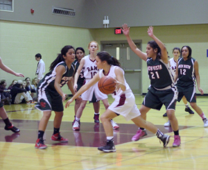 Freshman Alina Bell dribbles around the defense while junior Leah Sosland gets gets ready for the pass. Photo by Debi Davis.